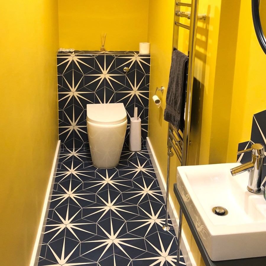 blue and white starburst tiles in a yellow bathrrom